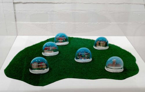 Olaf Nicolai, Souvenir Heimat. Schneekugeln. Sechs Rekonstruktionen, 1997, Kunststoff, Kunstrasen © VG Bild-Kunst, Bonn 2024, Ausstellungsansicht, Ein kristallner Tag. Winterbilder von Schneeweiß bis Nebelgrau, BLMK Frankfurt (Oder), 2024, Foto: Bernd Schönberger
